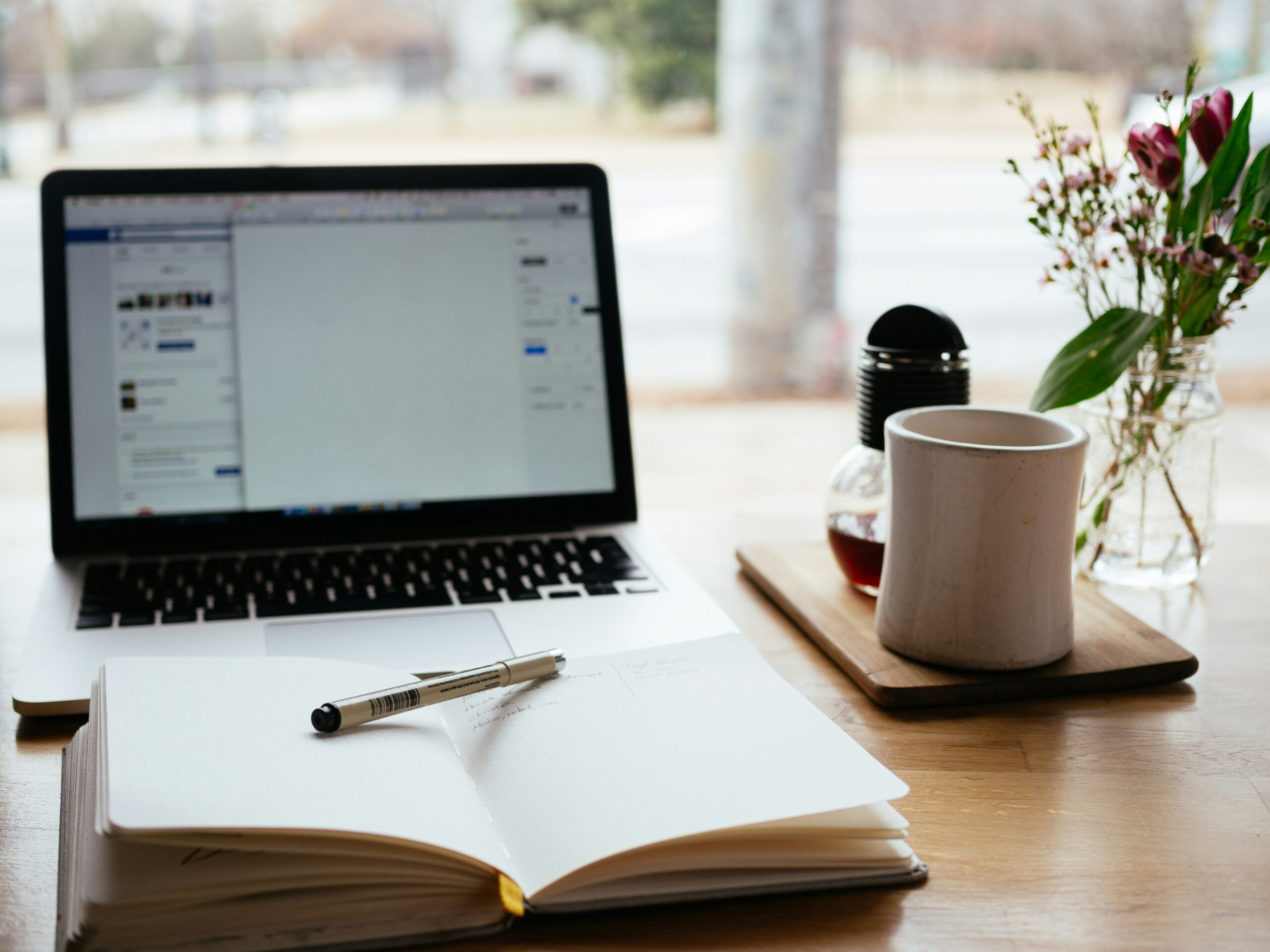 Open laptop with book and a coffee mug.